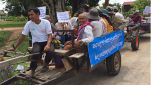 Photo of elderly women holding up signs for an elderly rights awareness campaign. They are on top of a tractor truck.