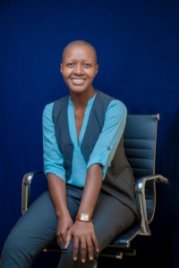 A portrait photo of a woman/of Mengo sitting on an office chair and facing the camera.
