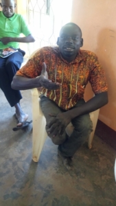 A photo of Oluka John seated and posing for the camera.