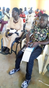 Hellen Amuron (in wheelchair) participating in a community advocacy meeting. Beside him is another participant.