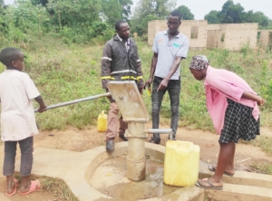 Fred Kateeto, Fisherfolk Ambassador (in grey branded Shirt) at one of the rehabilitated boreholes in Mukajja Village on 27th April 2023, while some of the community members fetch safe water.