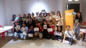 Group photo of participants with their painting canvases